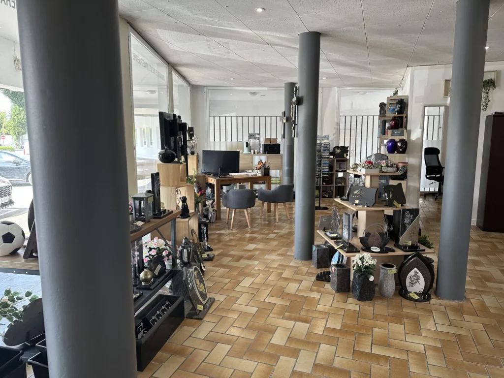 Vue d'ensemble de la salle d'exposition de marbrerie funéraire avec articles de souvenir et bureau